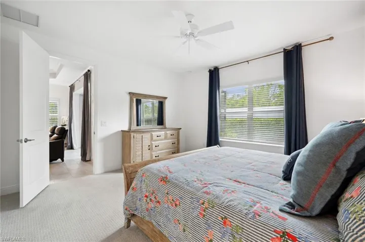 Carpeted bedroom with ceiling fan and multiple windows