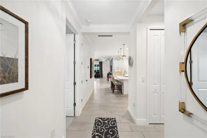 Hallway featuring ornamental molding and light tile flooring