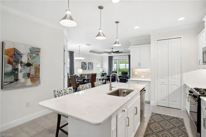 Kitchen with appliances with stainless steel finishes, a kitchen island with sink, sink, tasteful backsplash, and ceiling fan