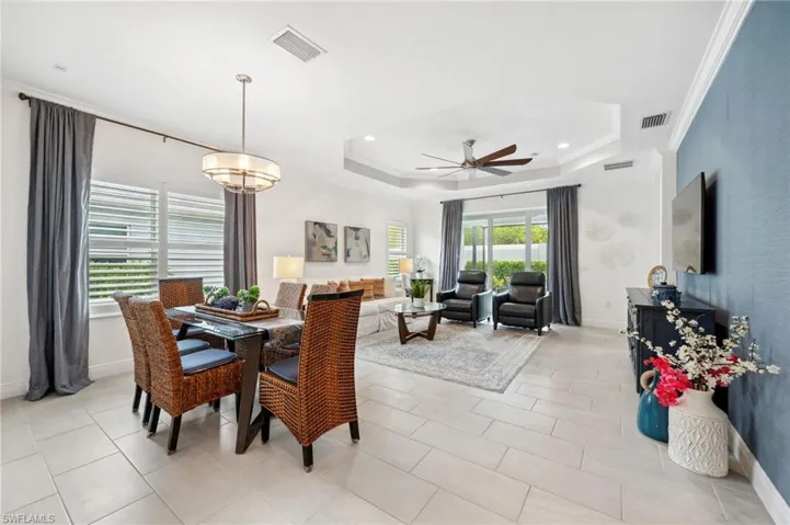 Tiled dining space with a tray ceiling, ornamental molding, and ceiling fan