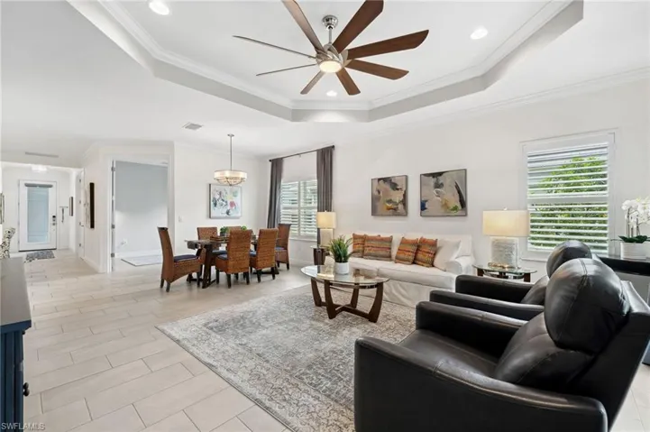 Tiled living room featuring crown molding, plenty of natural light, ceiling fan, and a raised ceiling