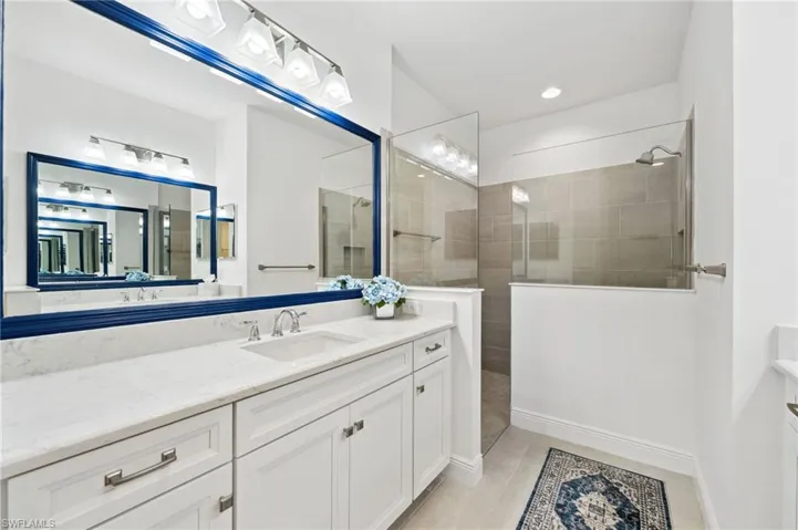 Bathroom featuring a shower with shower door, tile flooring, and vanity