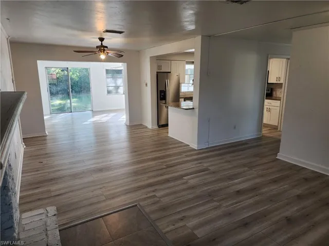 Unfurnished living room featuring ceiling fan and dark hardwood / wood-style floors