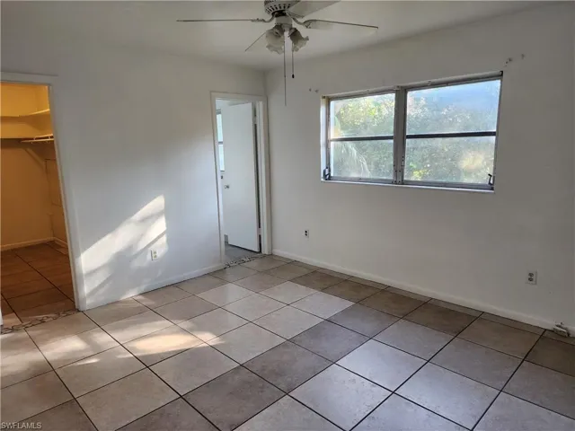 Unfurnished bedroom featuring ceiling fan, light tile patterned flooring, a walk in closet, and a closet