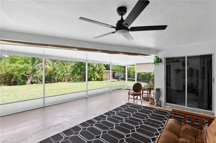 Sunroom / solarium with ceiling fan and view of wooded area