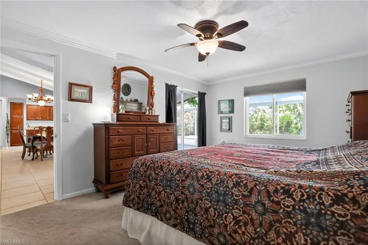 Bedroom featuring access to outside, light colored carpet, crown molding, a chandelier, and a ceiling fan