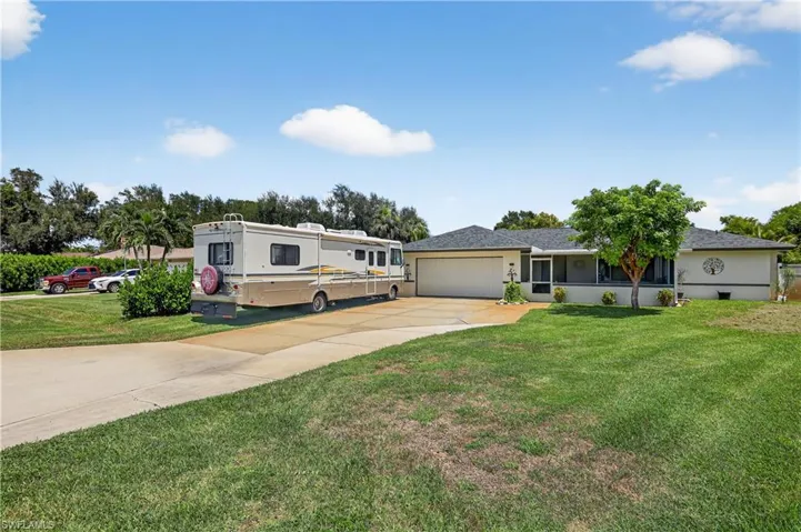 View of front facade featuring concrete driveway, a garage, a front lawn, and stucco siding