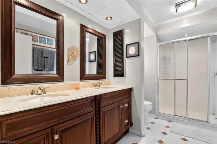 Bathroom featuring a shower stall, double vanity, light tile patterned floors, and recessed lighting