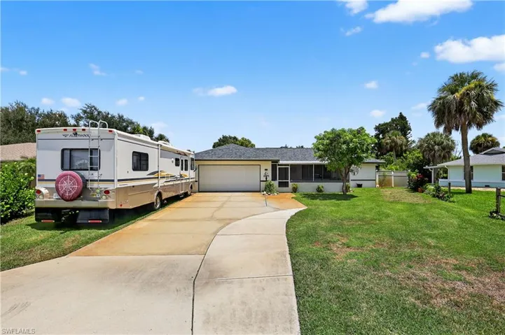 View of front of home with driveway, an attached garage, a front lawn, and a sunroom