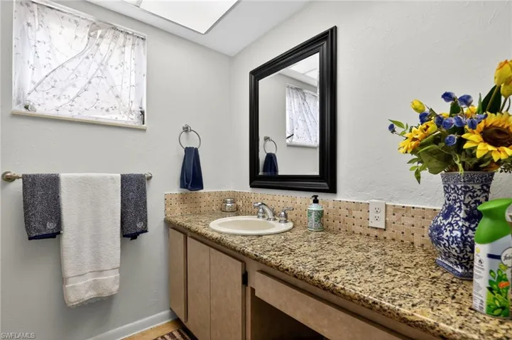 Bathroom with vanity, a textured wall, and healthy amount of natural light