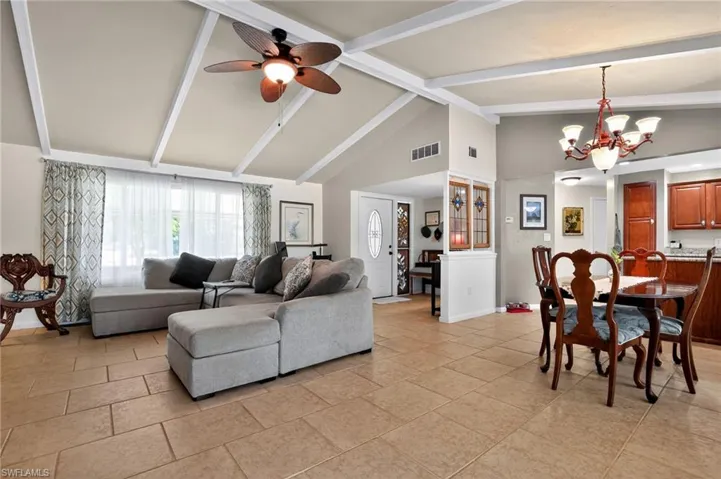 Living room featuring beamed ceiling, ceiling fan, a chandelier, high vaulted ceiling, and light tile patterned flooring