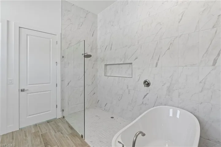 Bathroom featuring a walk in shower, a soaking tub, and wood tiled floors