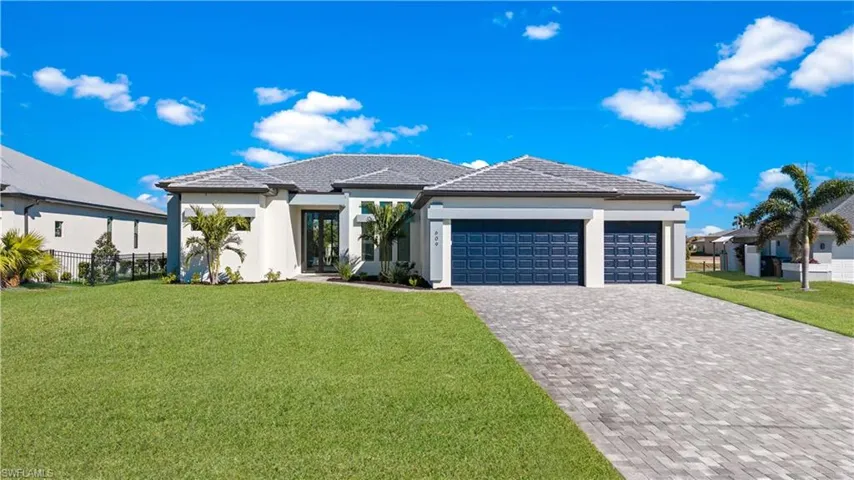 Prairie-style house with a front lawn, stucco siding, an attached garage, decorative driveway, and a tiled roof