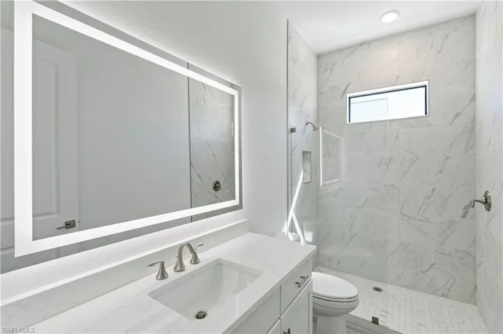 Bathroom with a marble finish shower and vanity