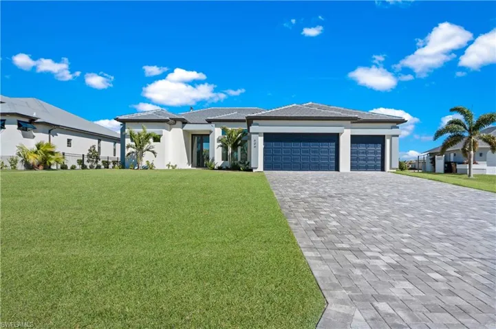 Prairie-style house featuring a front yard, an attached garage, decorative driveway, and stucco siding