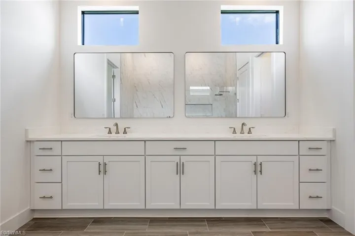 Bathroom with double vanity, a marble finish shower, and wood tiled floors