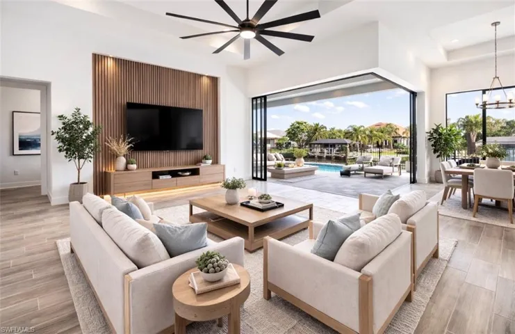 Living room with wood finish floors, a raised ceiling, a ceiling fan, and hanging lights