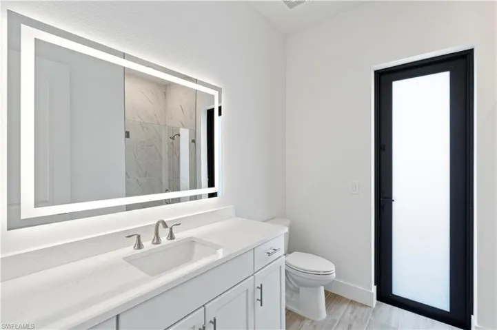Full bathroom with vanity, a marble finish shower, and light wood-type flooring