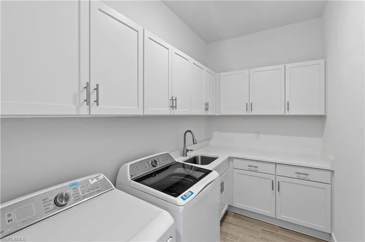 Laundry room featuring washer and dryer, cabinet space, and wood finish floors