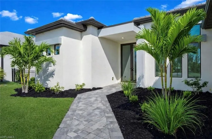 View of exterior entry with stucco siding and a yard