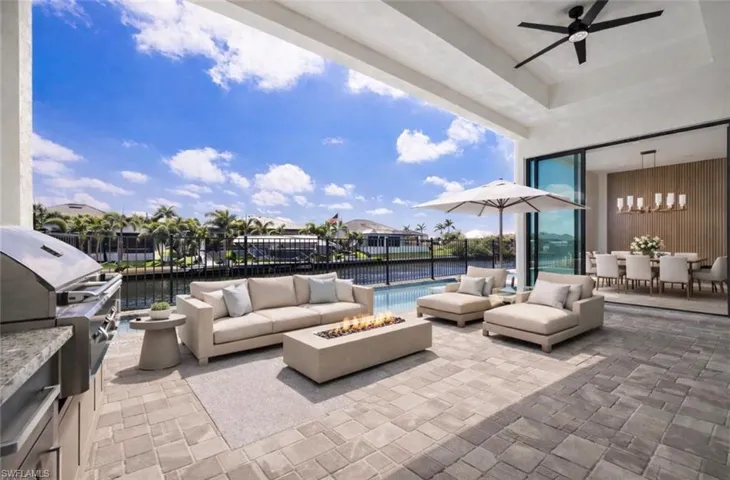 View of patio / terrace with a fire pit, a grill, an outdoor living / dining area, ceiling fan, and a water view/VIRTUALLY STAGED