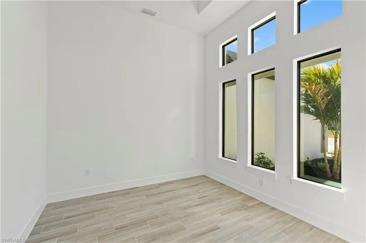 Unfurnished room with a high ceiling and wood finish floors