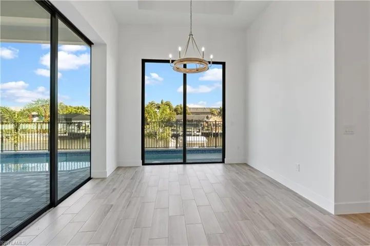 Spare room featuring a chandelier, wood tiled floors, and a raised ceiling