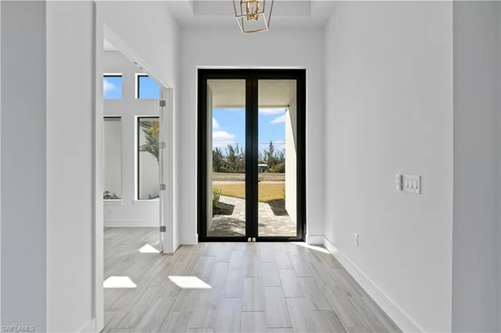 Doorway to outside with wood finish floors, french doors, hanging lights, and a high ceiling