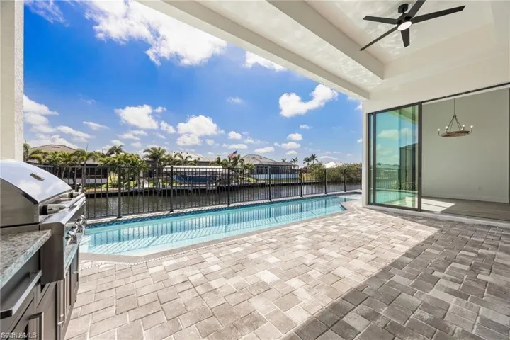 View of swimming pool with patio surround, grilling area, a water view, and a residential view