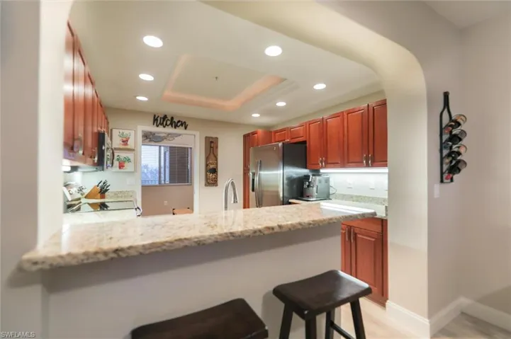 Kitchen featuring a breakfast bar, light stone countertops, stainless steel appliances, and kitchen peninsula