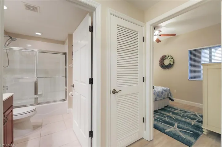 Full bathroom featuring ceiling fan, enclosed tub / shower combo, tile patterned floors, toilet, and vanity