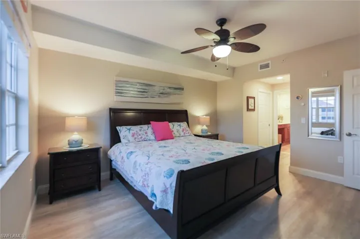 Bedroom with light wood-type flooring, ensuite bathroom, and ceiling fan