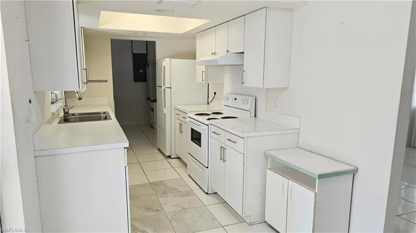 Kitchen featuring tasteful backsplash, white cabinets, light tile patterned floors, sink, and white electric stove