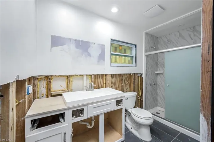 Bathroom with recessed lighting, toilet, vanity, a shower stall, and tile patterned floors