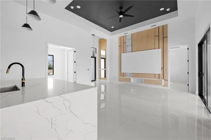 Kitchen featuring a sink, brown cabinetry, a tray ceiling, modern cabinets, and a ceiling fan