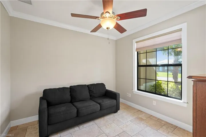 Living area with stone tile floors, crown molding, and ceiling fan