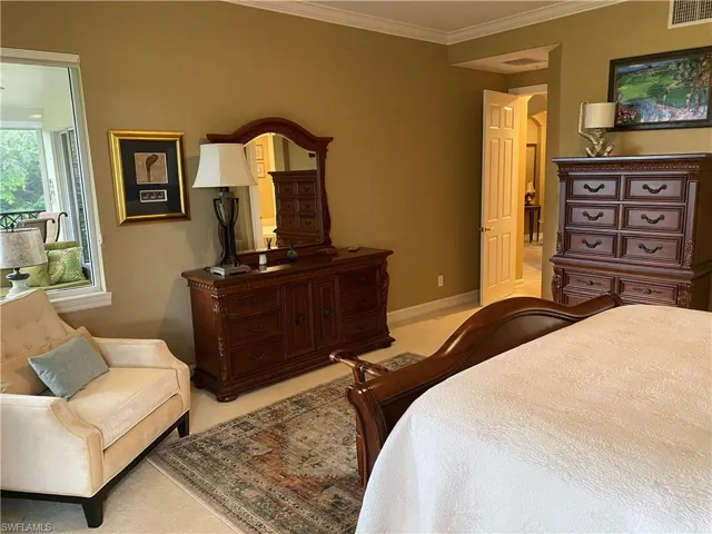 Bedroom with ornamental molding and light colored carpet