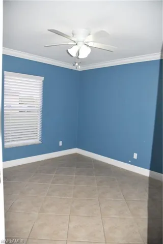 Unfurnished room featuring ornamental molding, light tile patterned flooring, and ceiling fan