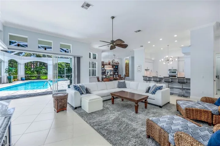 Tiled living room featuring ceiling fan with notable chandelier and crown molding
