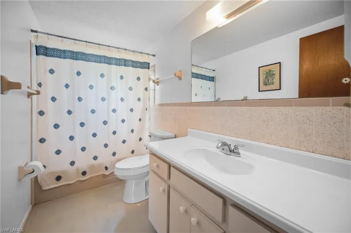 Bathroom featuring a single vanity with an integrated sink, polished chrome faucet, and a large wall-mounted mirror