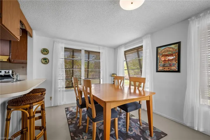 Dining area with multiple windows featuring blinds and sheer white curtains