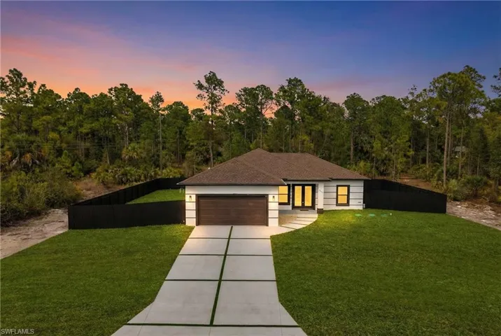 View of front facade featuring driveway, a garage, and roof with shingles