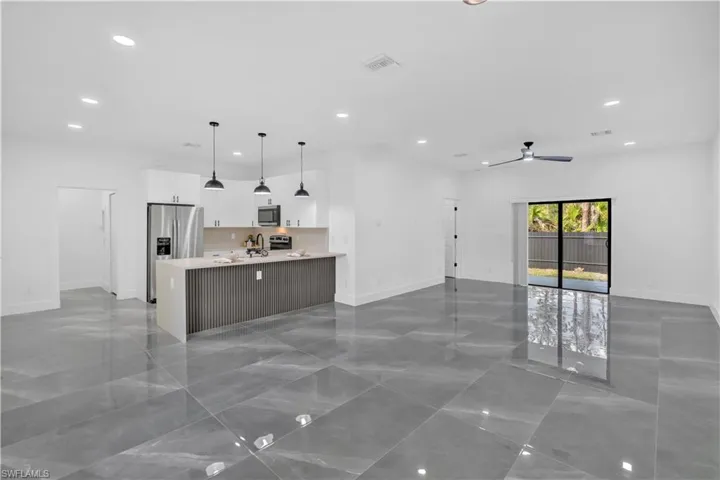 Kitchen with open floor plan, white cabinetry, a peninsula, and stainless steel appliances