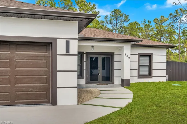 Property entrance featuring roof with shingles, stucco siding, french doors, and a garage