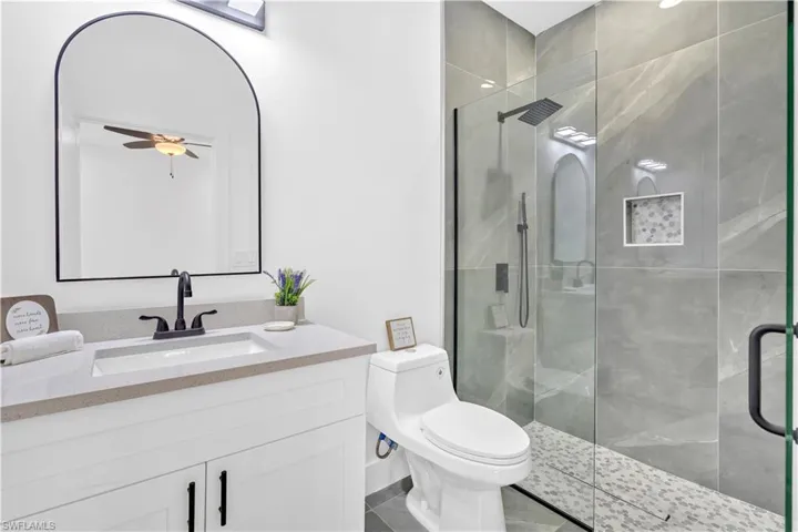 Full bathroom with a shower stall, vanity, and ceiling fan
