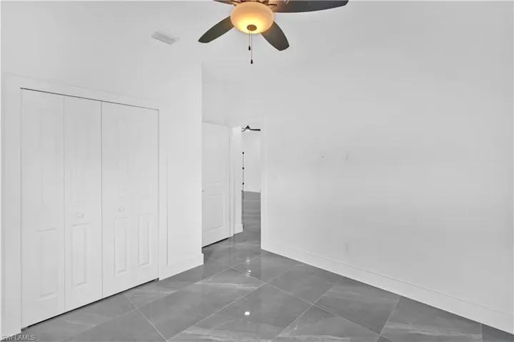 Unfurnished bedroom with ceiling fan and a closet