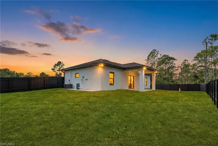 Rear view of house with stucco siding, a patio, and a fenced backyard