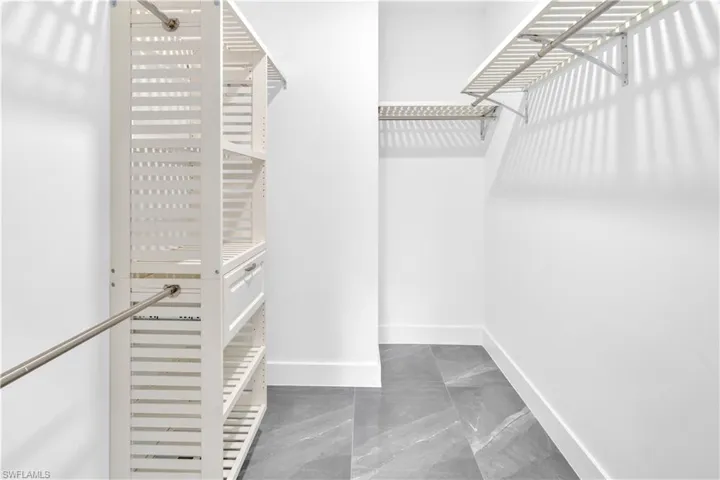 Walk in closet featuring light marble finish flooring and radiator