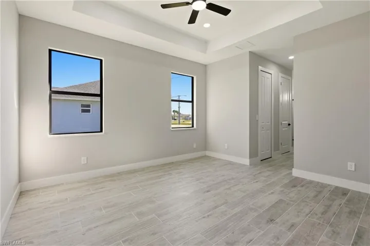 Bedroom featuring a raised ceiling, wood tiled floors, recessed lighting, and a ceiling fan