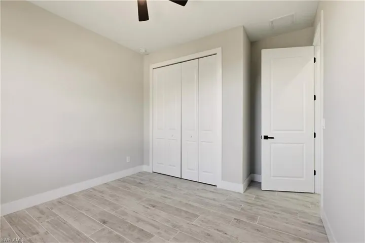 Unfurnished bedroom featuring wood finish floors, a ceiling fan, and a closet